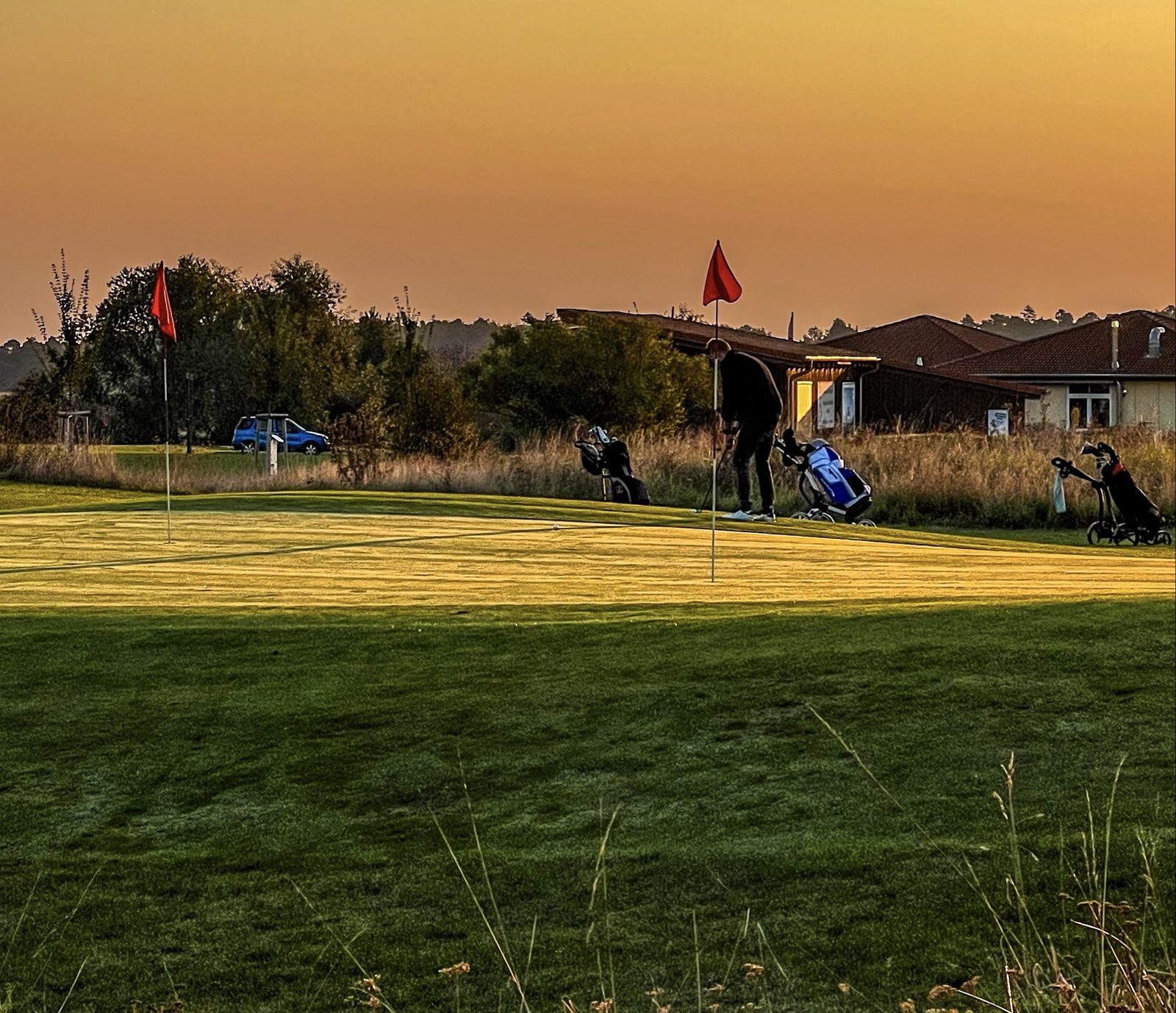 Golfer beim Putten auf dem Grün der Golfrange Nürnberg im goldenen Abendlicht