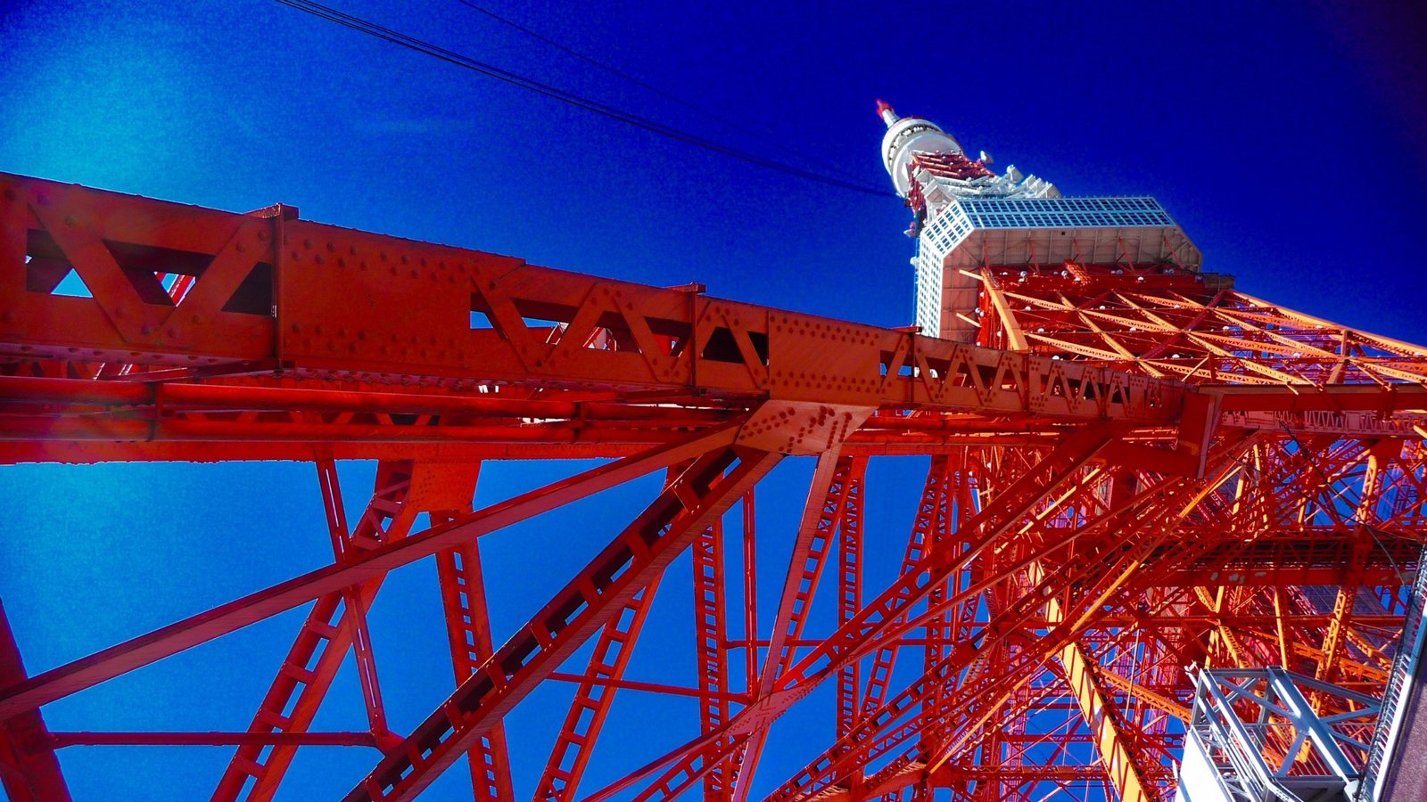 Orange-weiße Stahlkonstruktion des Tokyo Tower von unten vor tiefblauem Himmel