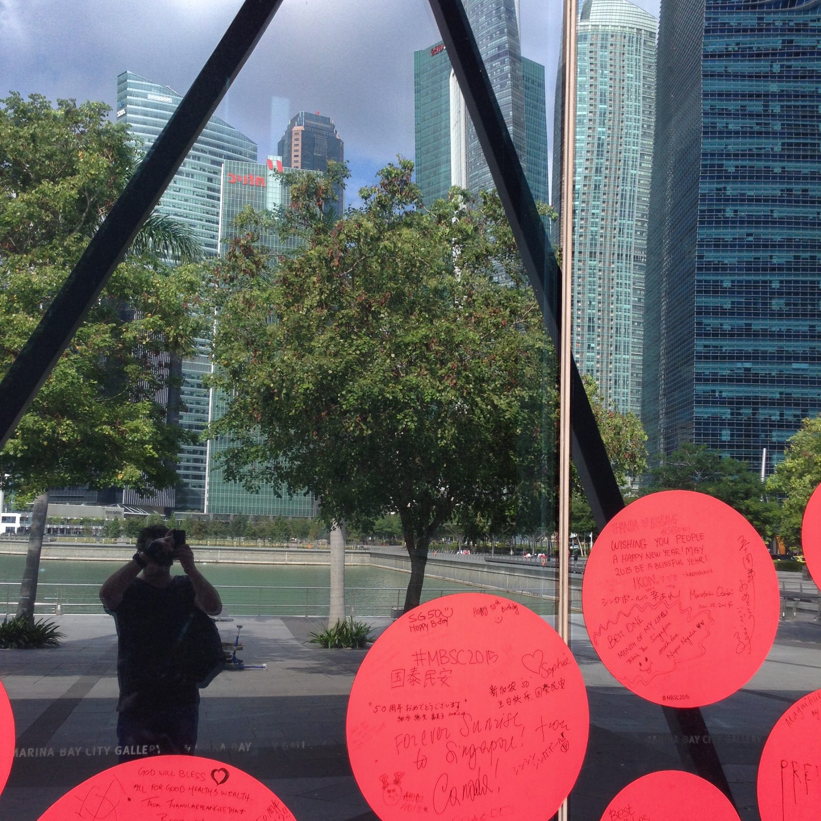 Spiegelbild des Fotografen in einer Glasscheibe der Marina Bay City Gallery mit SG50-Glückwunschkreisen