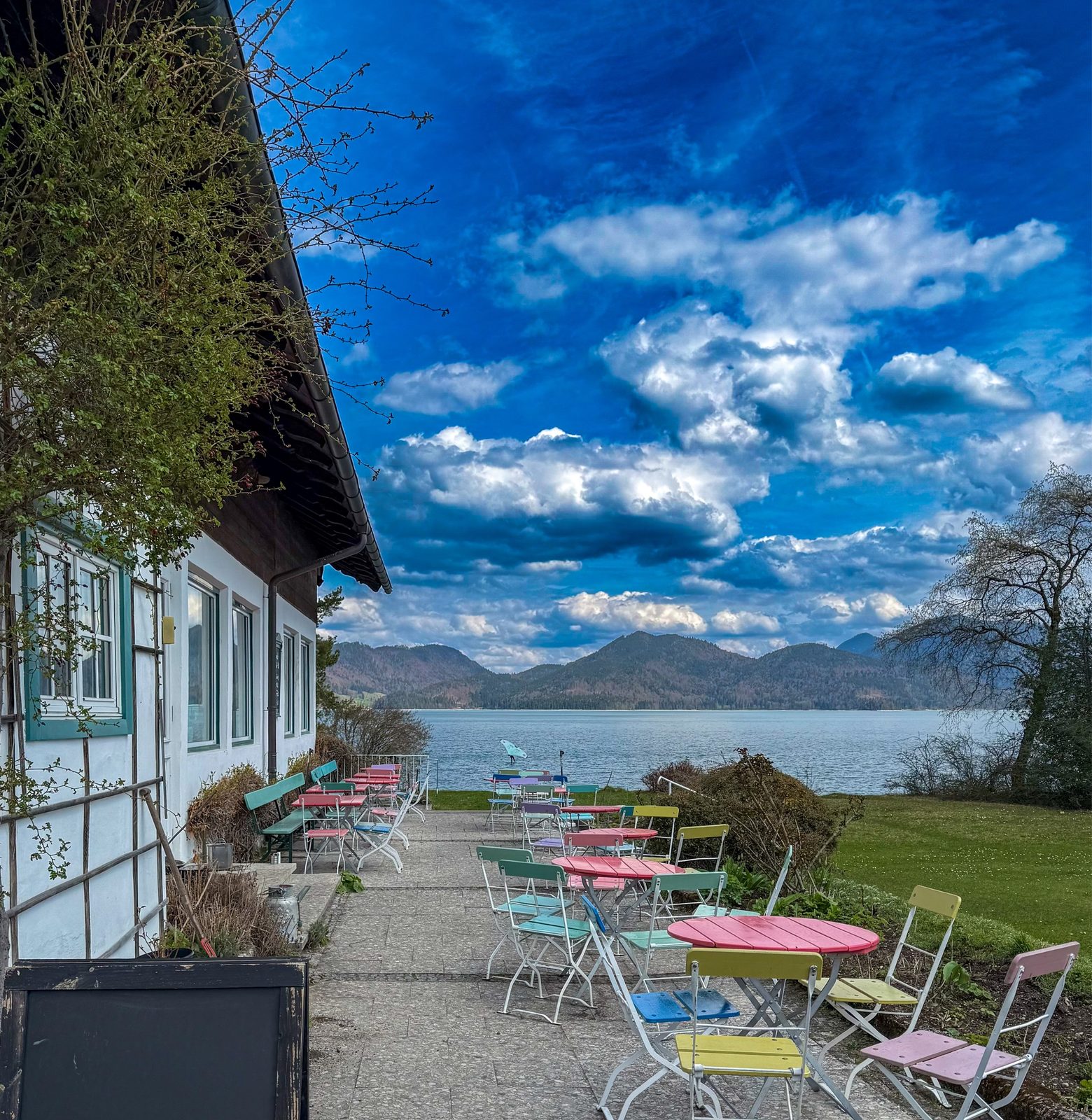 Seeterrasse mit bunten Klappstühlen direkt am Ufer des Walchensees