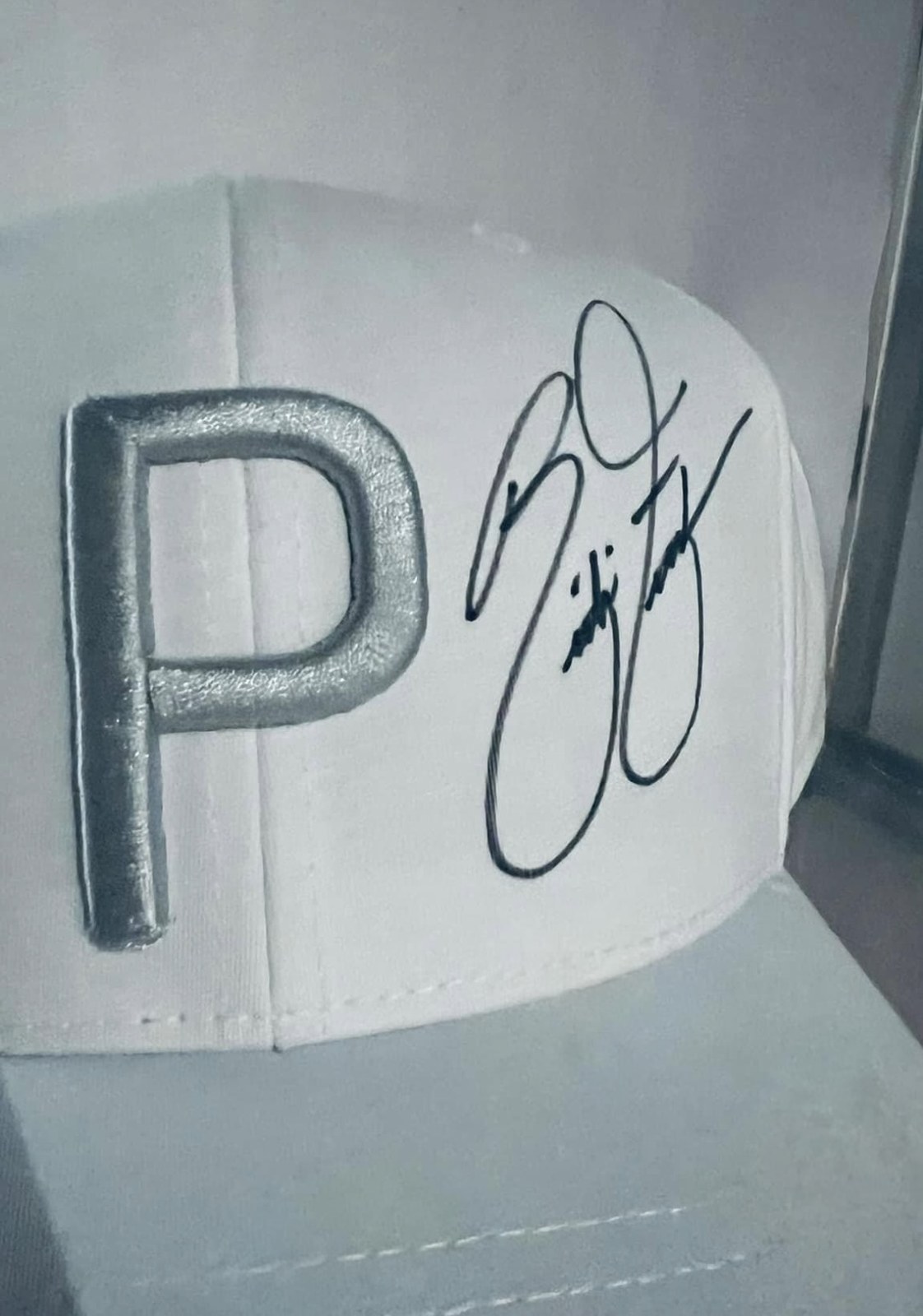 Weiße Puma-Kappe mit silbernem P-Logo und der handschriftlichen Unterschrift von Rickie Fowler