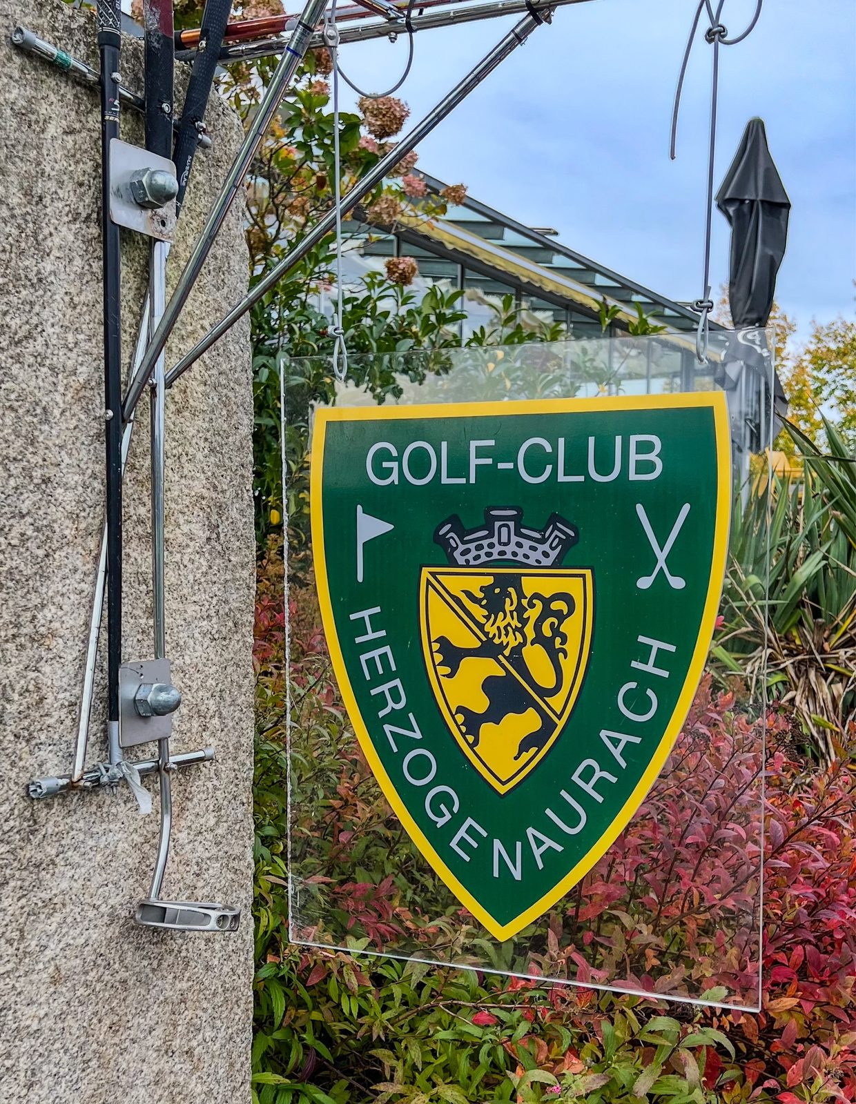 Grün-gelbes Vereinswappen des Golf-Club Herzogenaurach mit gekreuzten Schlägern und Flagge