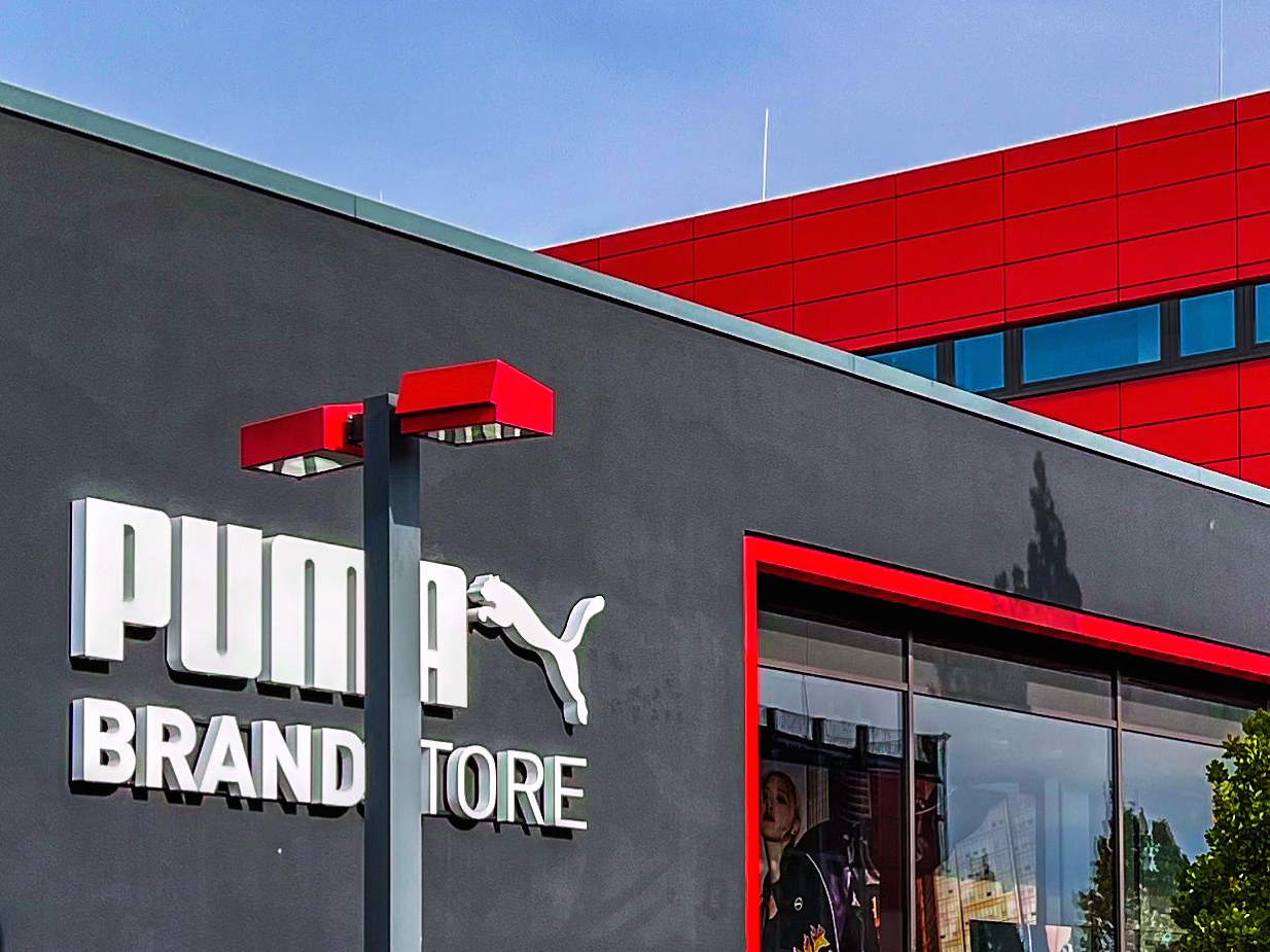Fassade des Puma Brand Store mit weißem Schriftzug und Puma-Logo vor rotem Gebäudeteil