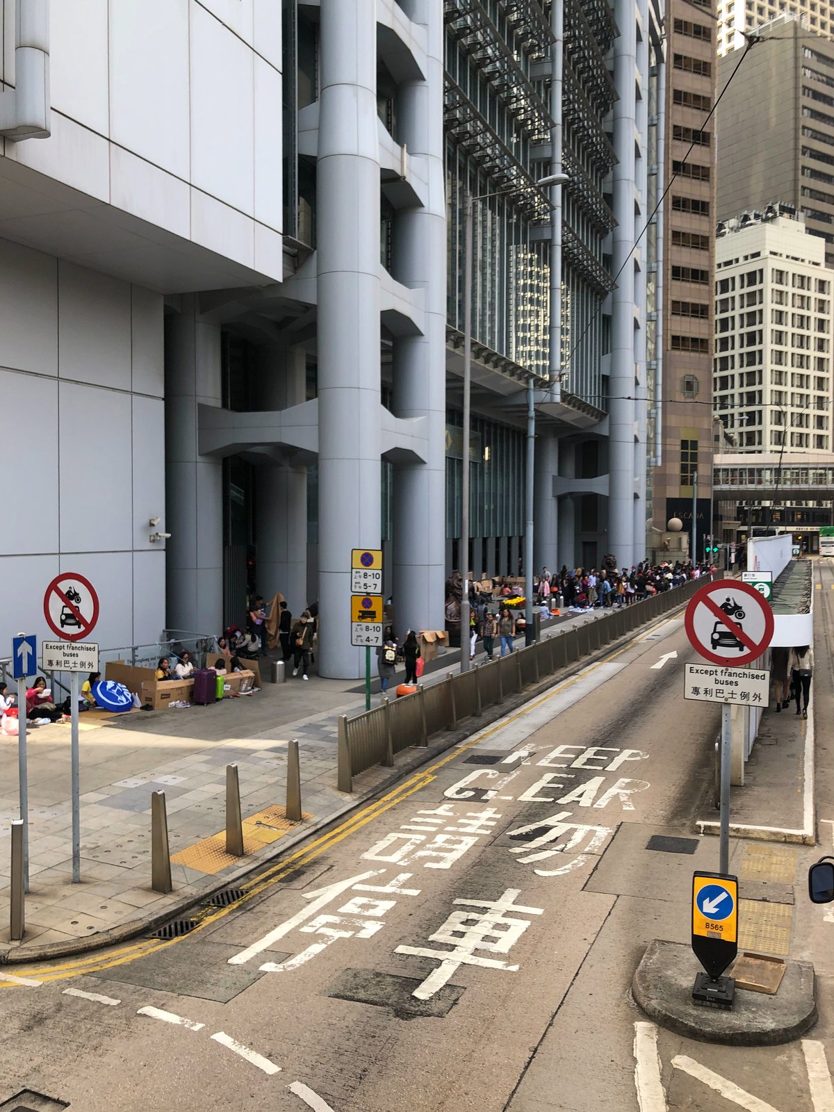 Menschen sitzen auf Kartons und Gepäck an einer abgesperrten Straße in Admiralty, Hongkong, an einem Sonntag