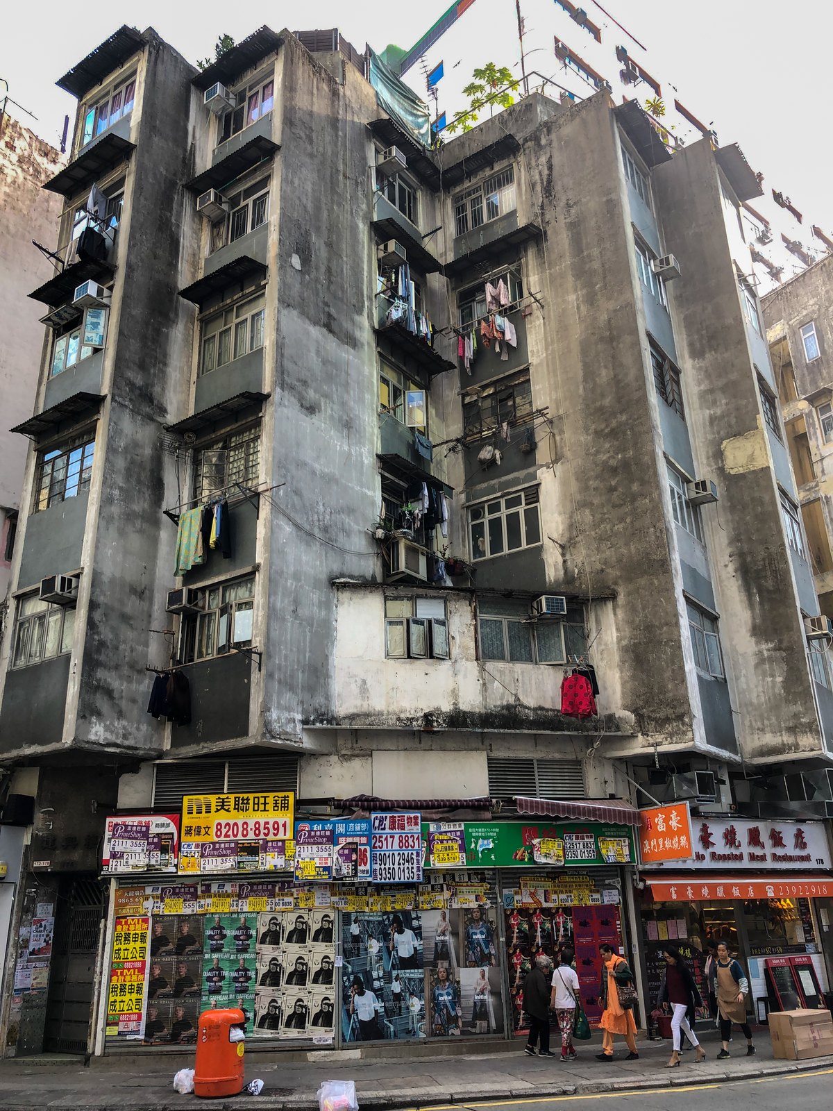 Verwitterter Wohnblock in Hongkong mit Wäscheleinen an fast jedem Fenster
