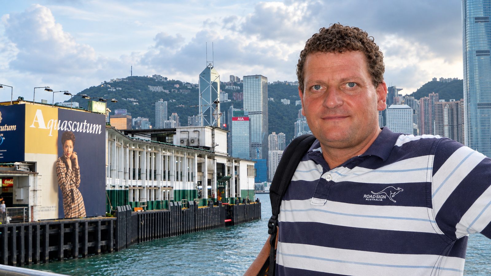 Torsten Fink vor dem Star-Ferry-Pier, dahinter die Skyline von Hong Kong Island mit dem Bank of China Tower