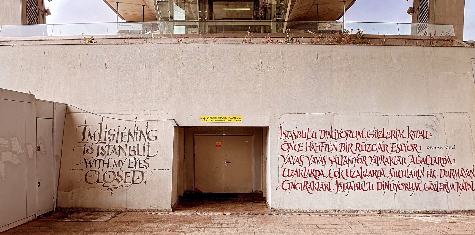 Kalligrafie-Wand an einem Metroausgang mit dem Orhan-Veli-Gedicht auf Englisch und Türkisch