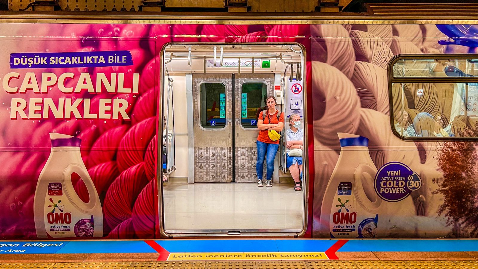 Frau in der Tür eines Istanbuler Metrowagens mit bunter Werbefolie