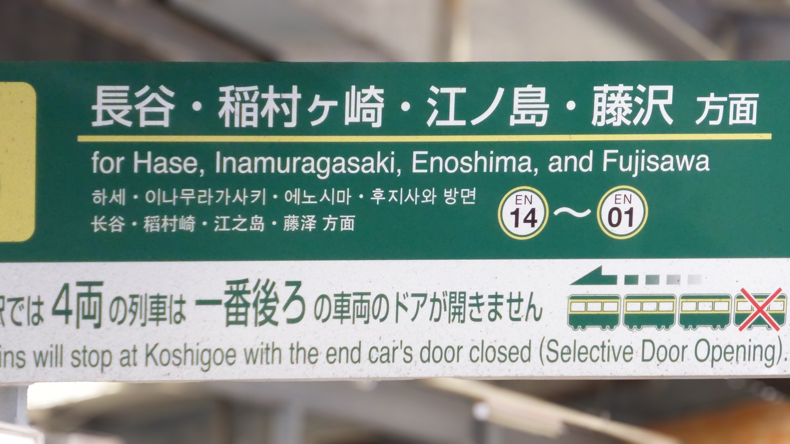Zweisprachiges Bahnhofsschild der Enoshima Electric Railway mit den Zielen Hase, Inamuragasaki, Enoshima und Fujisawa