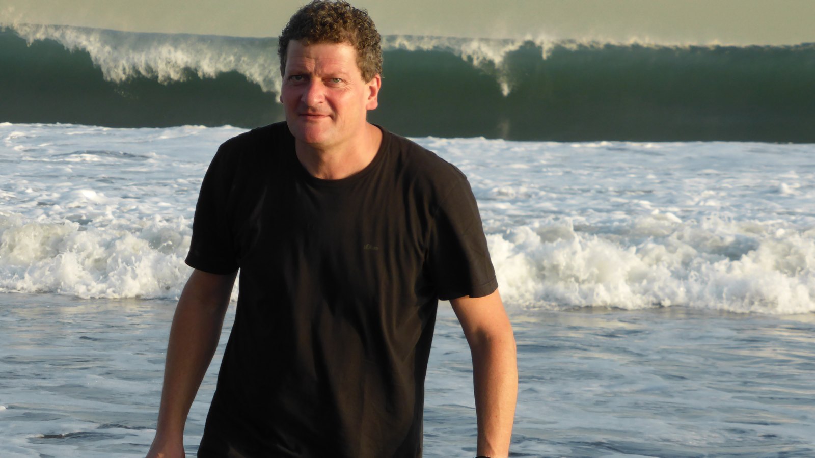 Torsten Fink am Strand von Kamakura, im Hintergrund eine sich brechende Welle