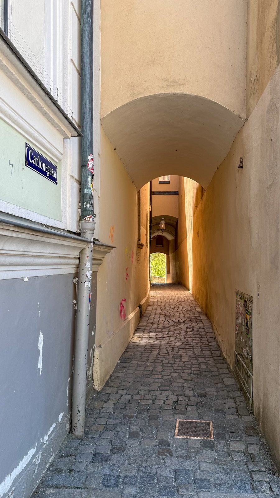 Enge, gewölbte Carlonegasse in Passau mit Kopfsteinpflaster und Blick ins Licht am Ende