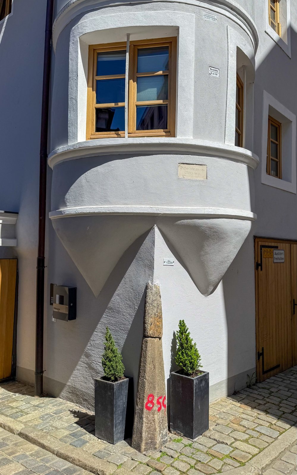 Hochwassermarken an einer Passauer Hausecke mit historischen Wasserständen und einem alten Grenzstein