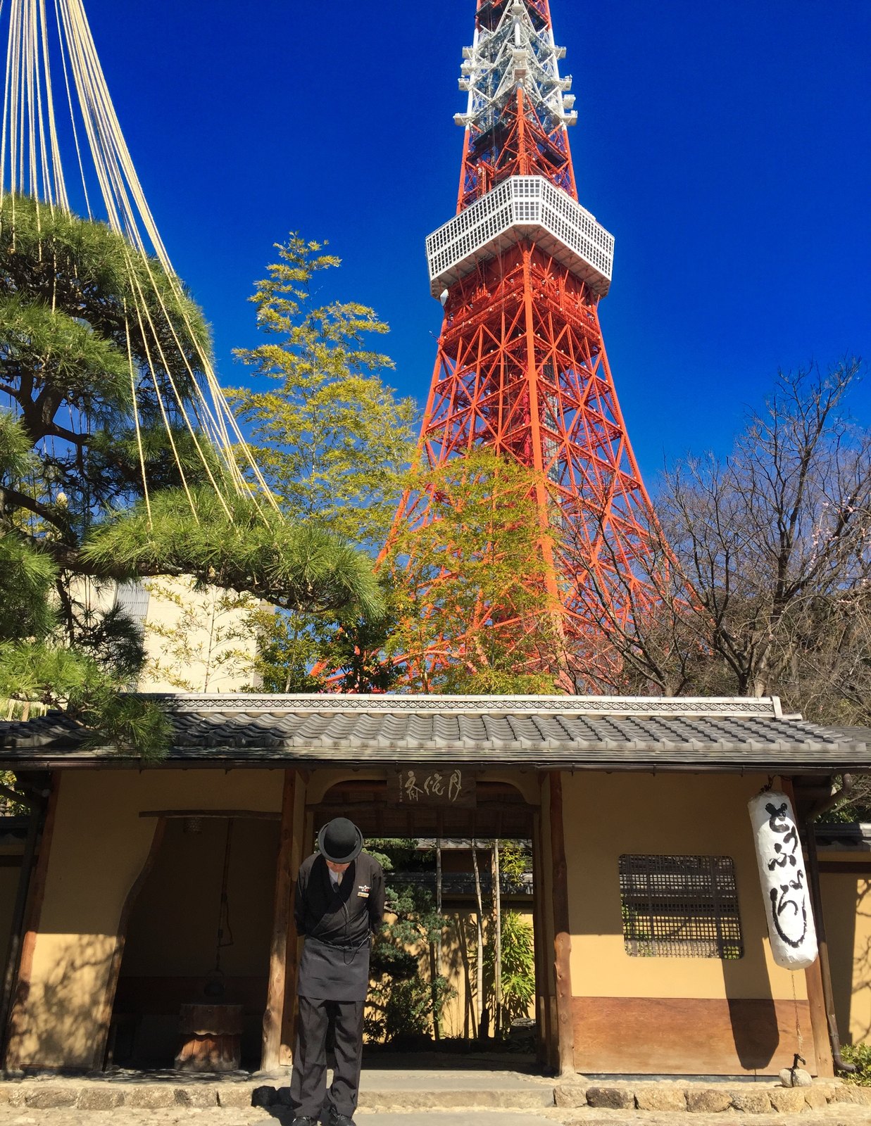 Angestellter des Restaurants Tofuya Ukai verbeugt sich zur Begrüßung am Eingang vor dem Tokyo Tower